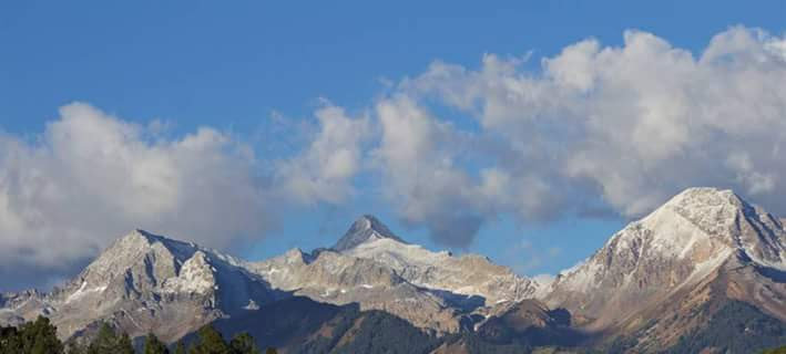Majestic Snow-capped Peaks Under Blue Skies Vista.jpg